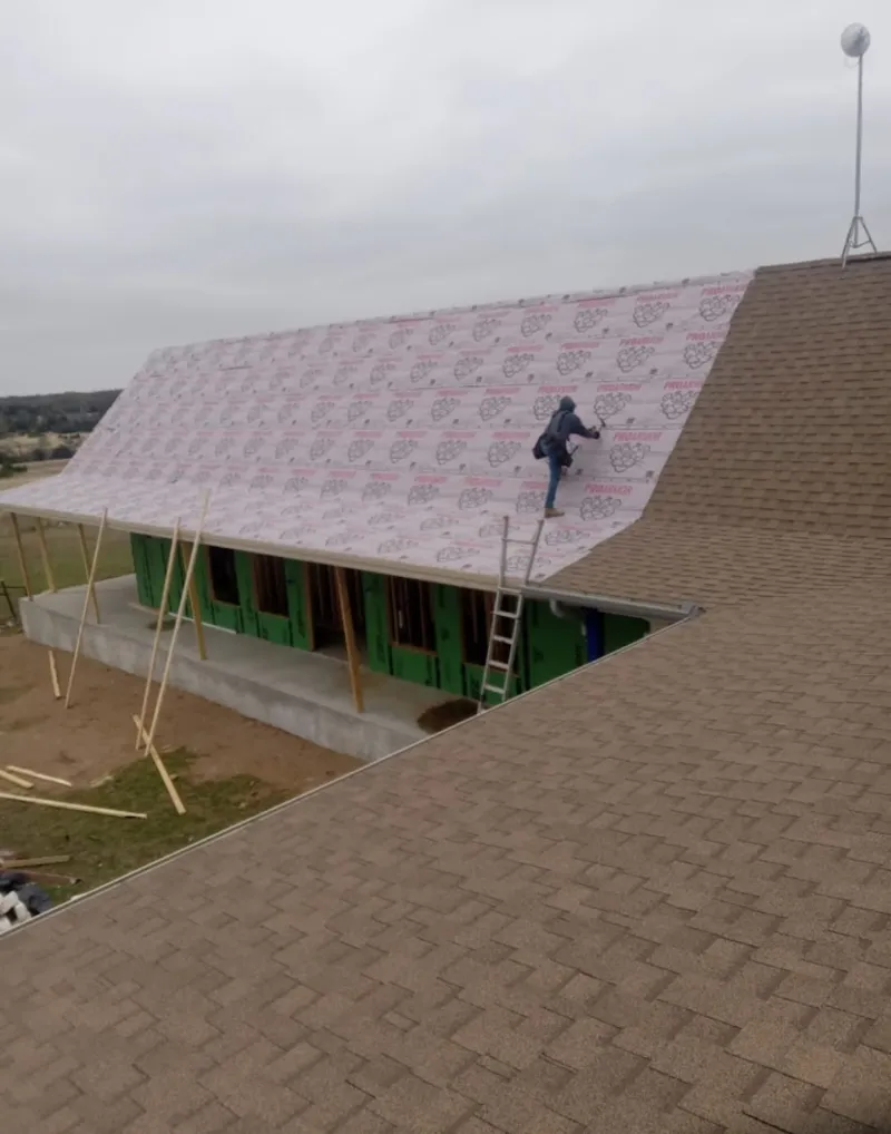 Worker preparing underlayment for a metal roof installation in Mount Morris
